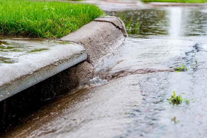 Stormwater flowing into street intake drain after a rainstorm.